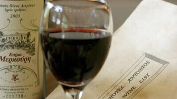 Une bouteille de vin Krivka Mezocheno, un verre de vin rouge et un menu orné d’un ruban rouge.