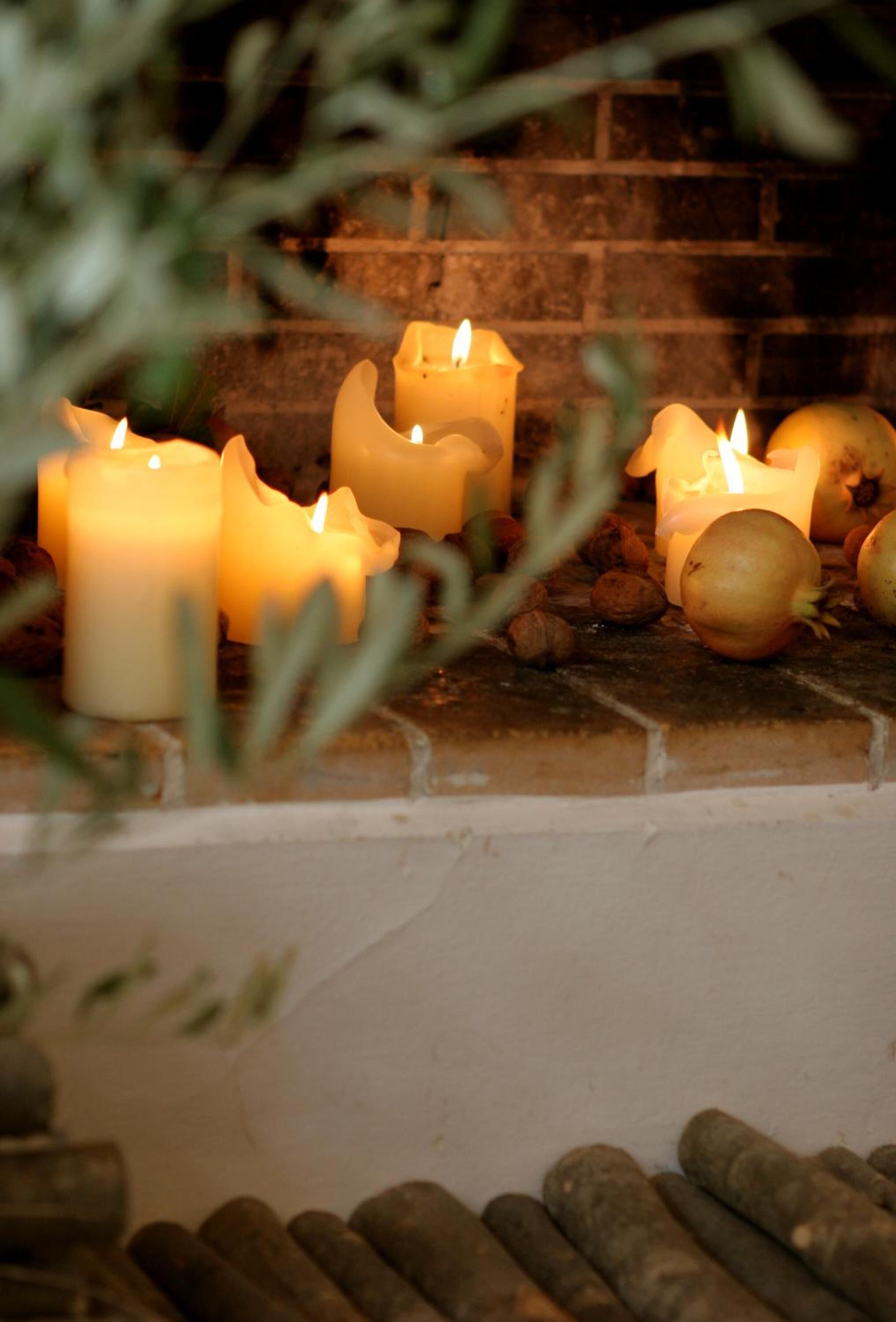 A fireplace with several lit candles and some onions.