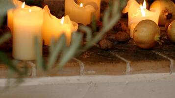A fireplace with several lit candles and some onions.