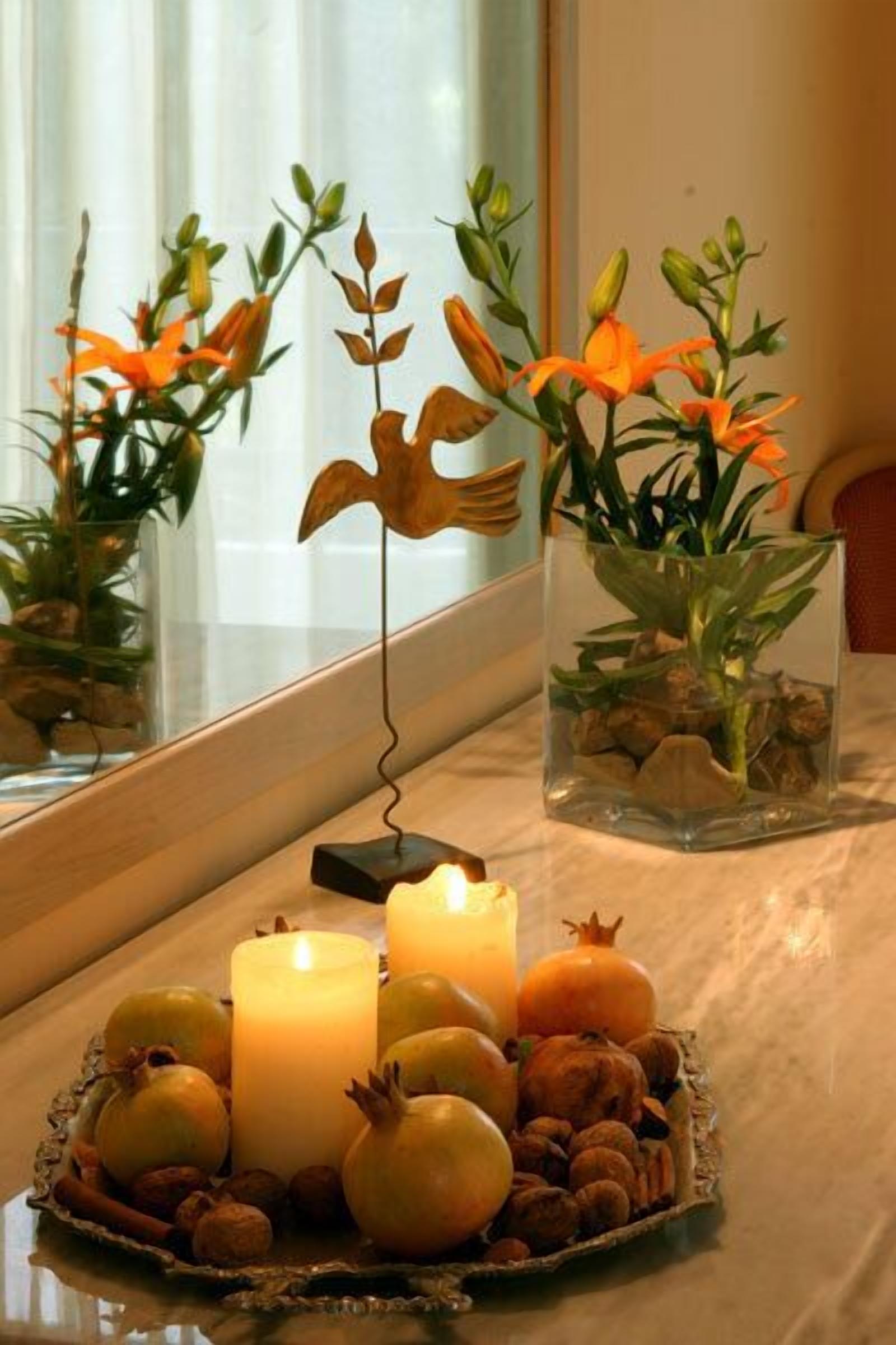 A table with candles, pomegranates, and a decorative bird.