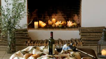 A cozy room with a fireplace, candles, a bottle of wine, and a blanket.
