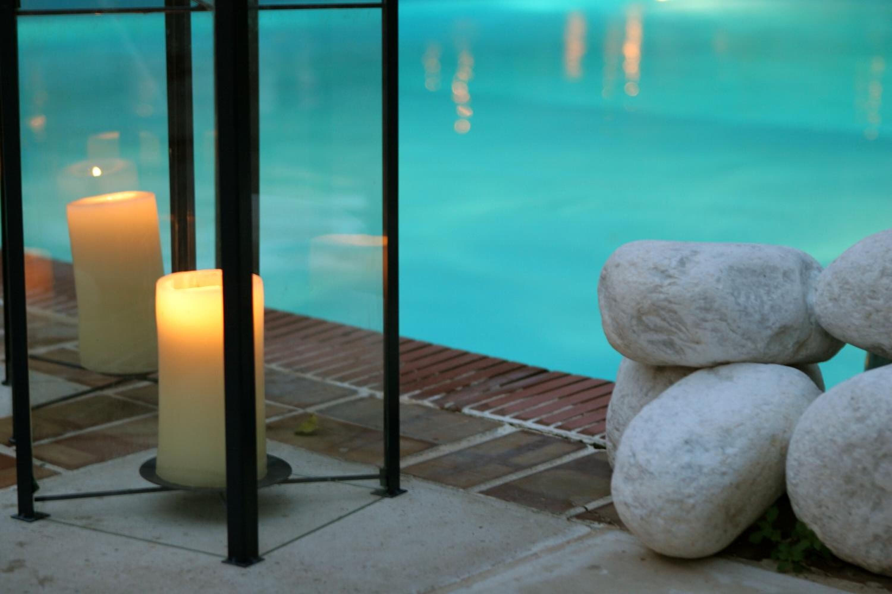 Un área junto a la piscina con velas y una pila de piedras.