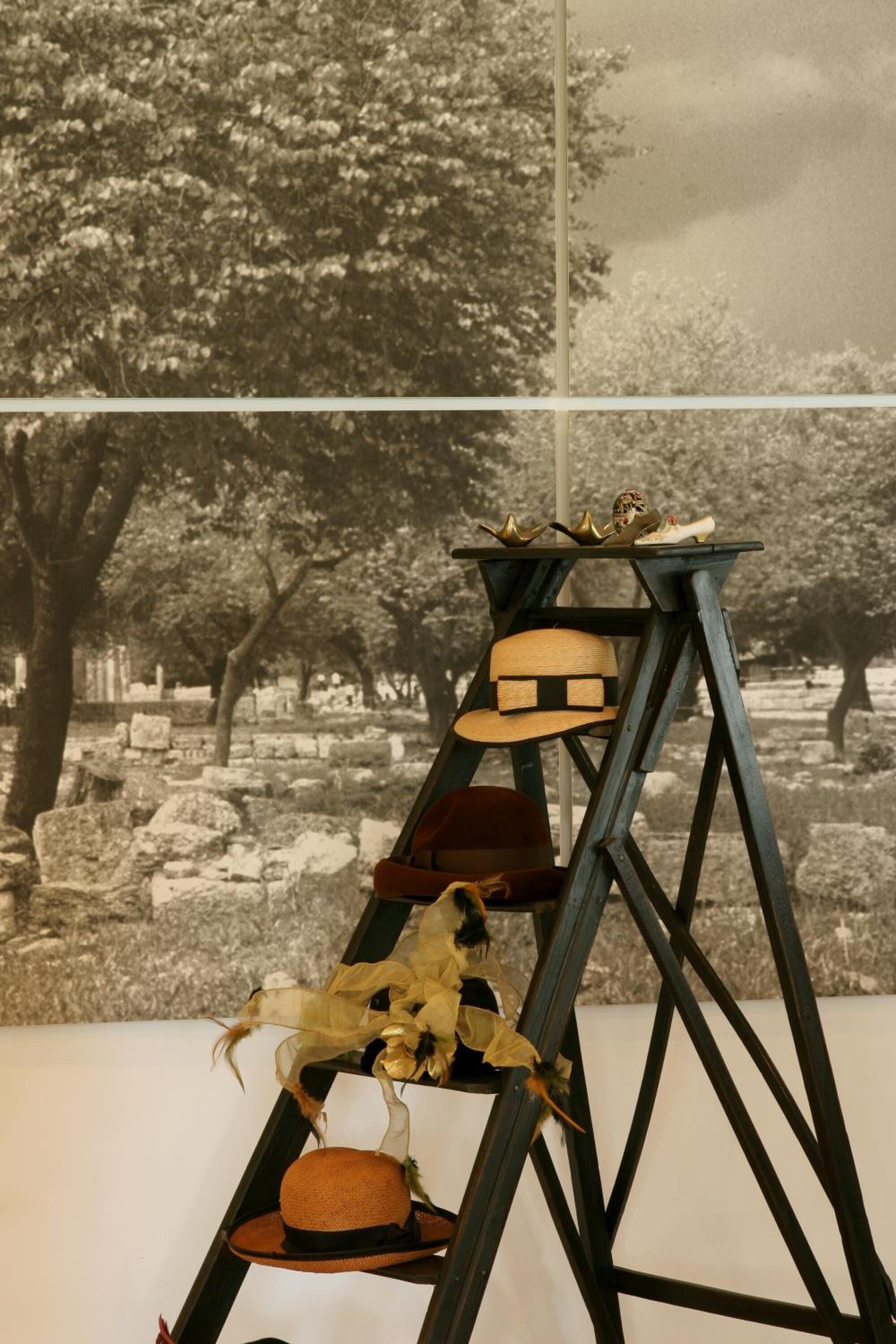 A black and white photograph of a cemetery with a wooden chair and hats on a table.