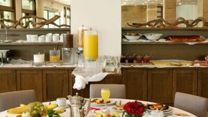 A breakfast buffet with various fruits, a pitcher, and a vase of flowers. - Antonios (Archaia Olympia)