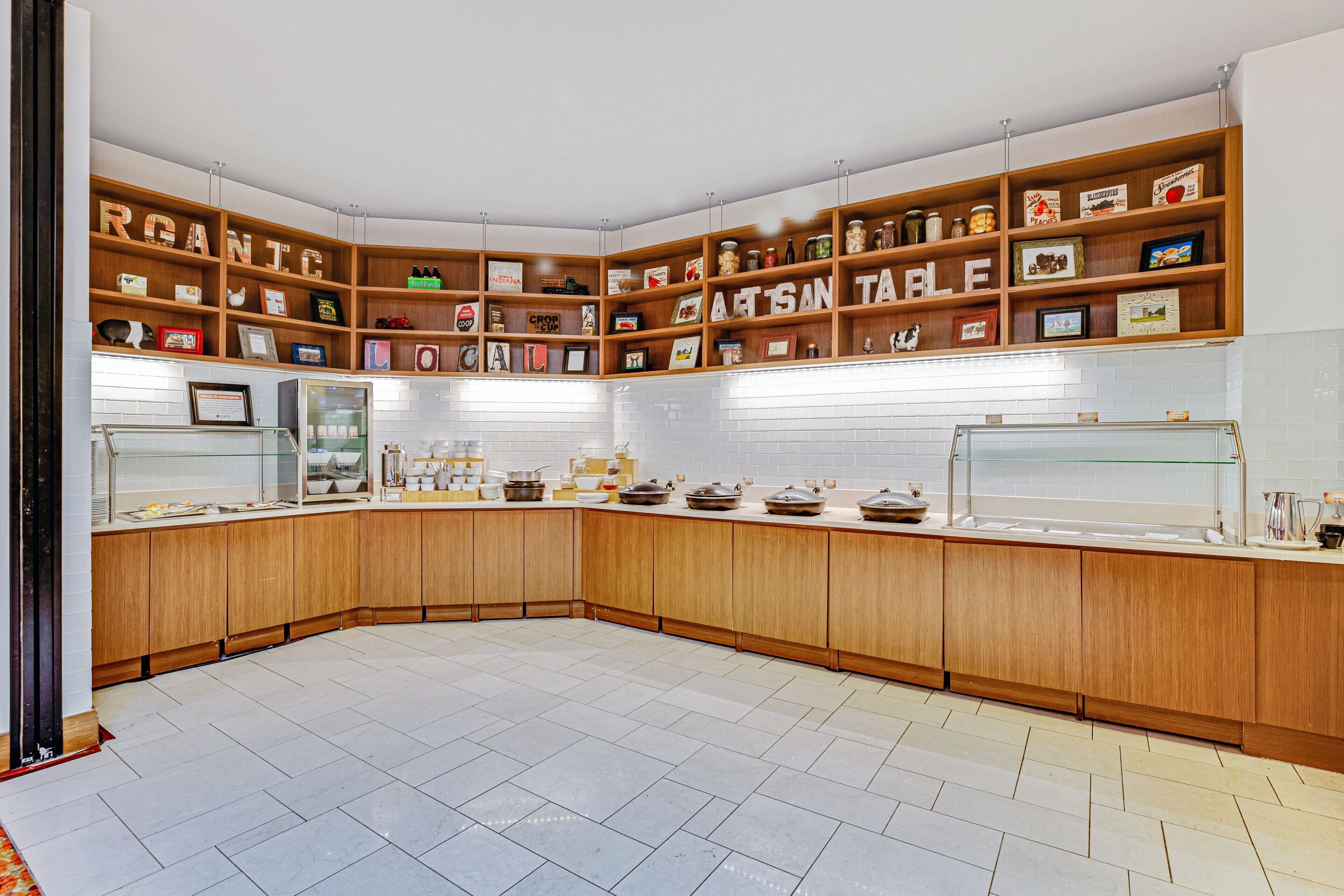 A kitchen with wooden cabinets, a central island, and shelves with various kitchen items.