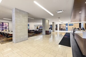A spacious lobby with a reception desk, seating area, and a view of the street outside.