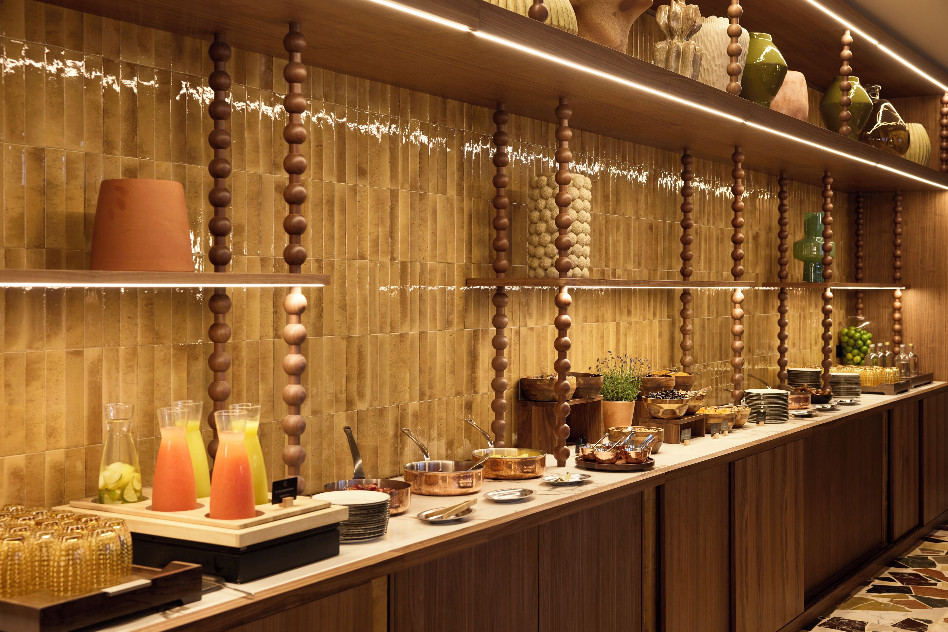 A buffet setup with various food items and beverages, wooden paneling, and a long counter.