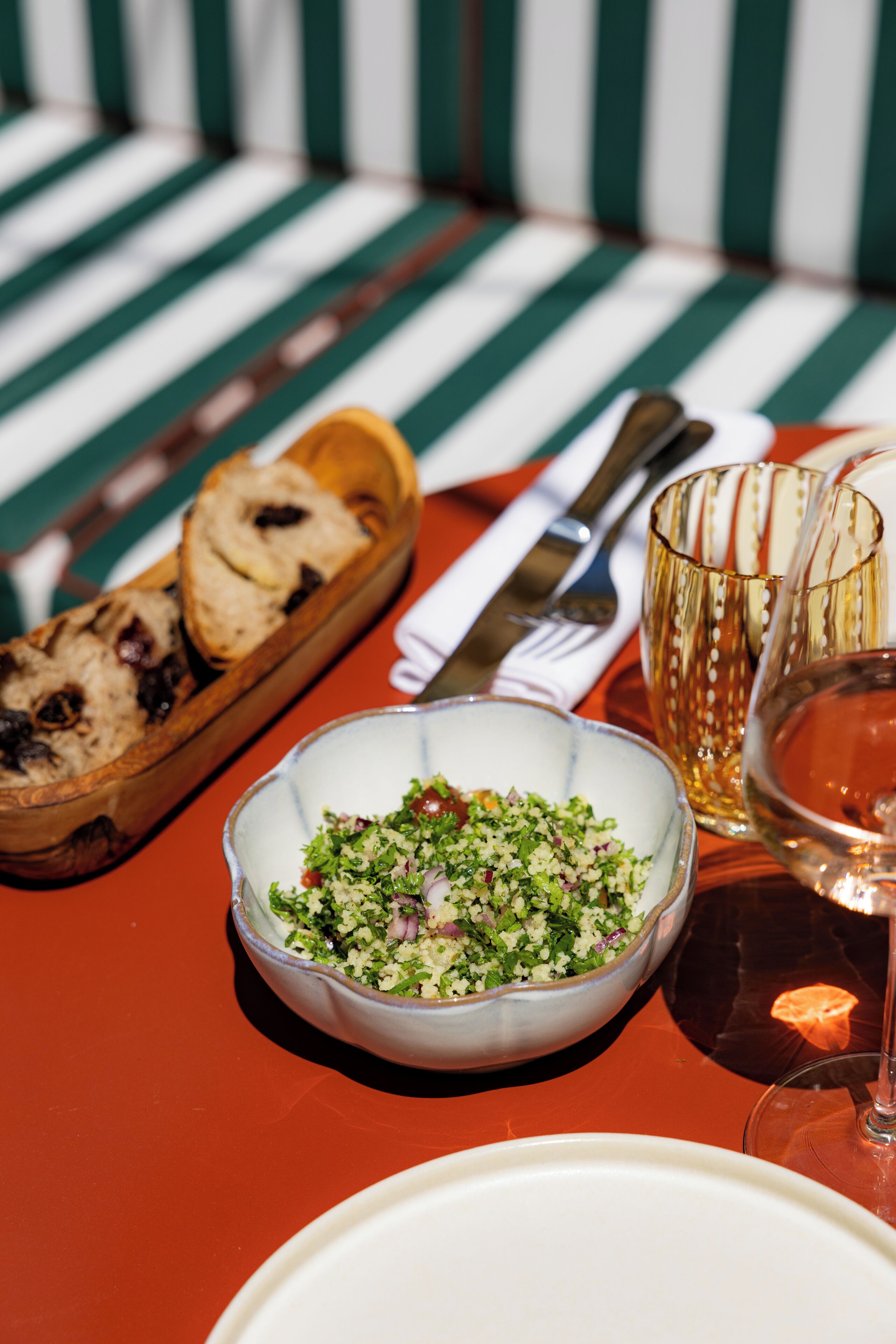 A dining table with a bowl of salad, a glass of wine, and a plate.