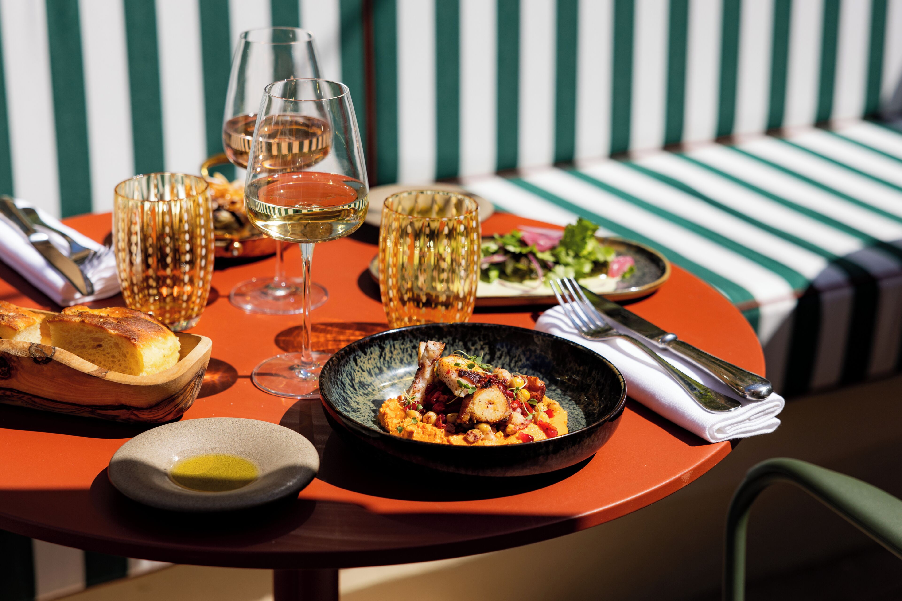 A dining table with a meal, wine glasses, and cutlery.