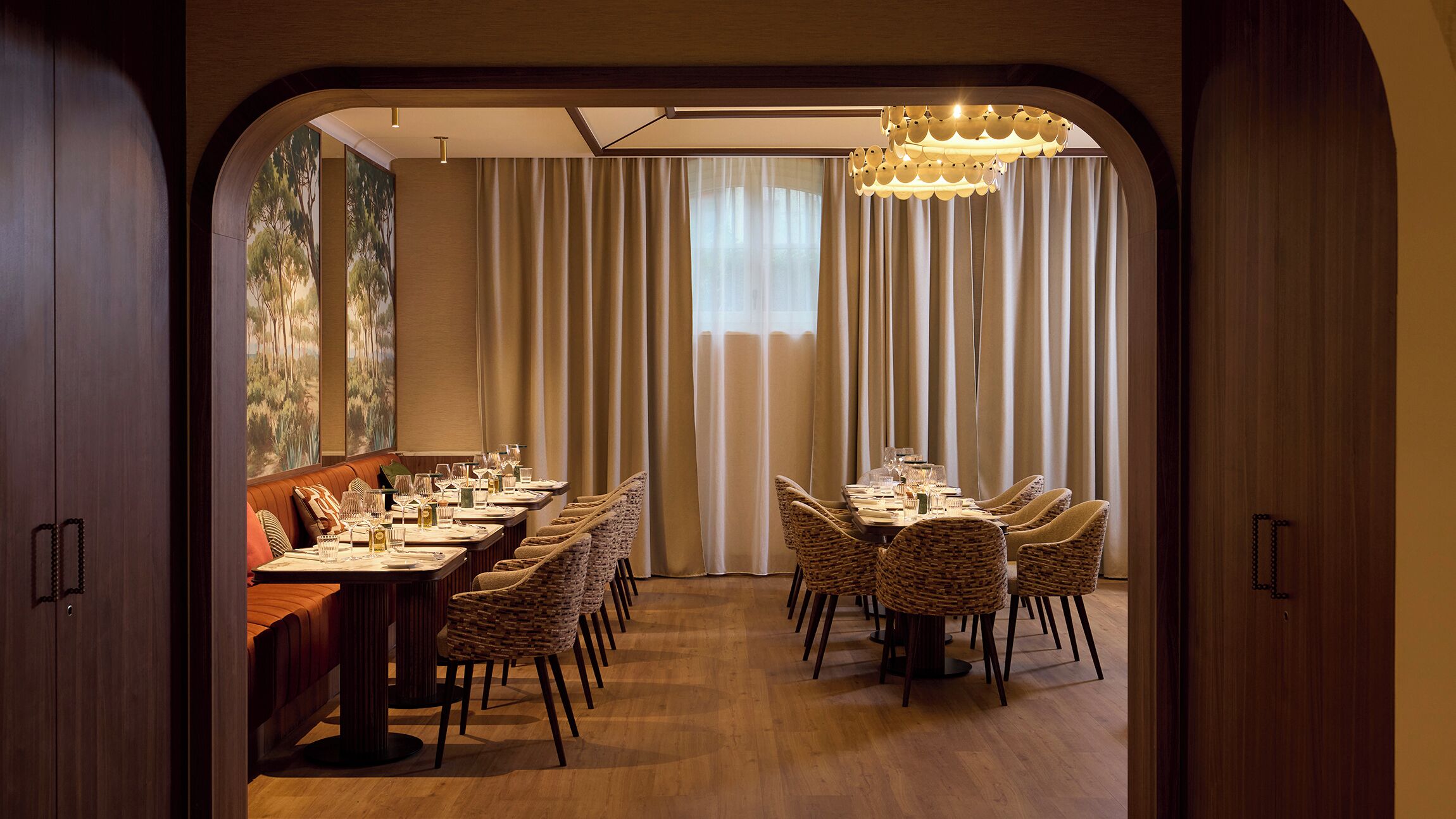 Un comedor con una mesa larga, sillas de mimbre y un candelabro.