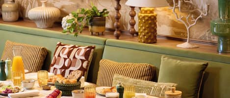 A dining area with a table set for breakfast, including plates, glasses, and a coffee pot.