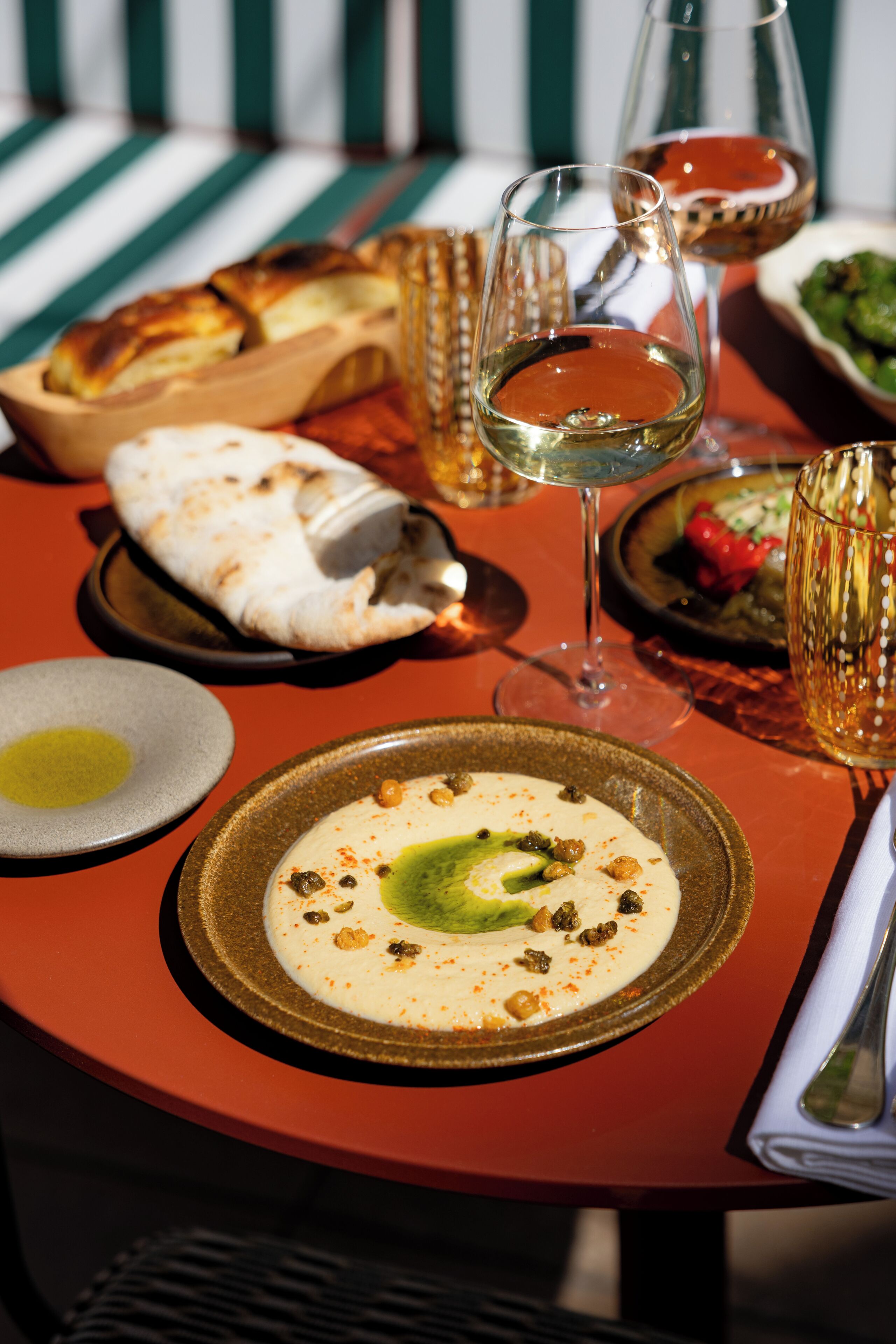 A dining table with a variety of dishes, glasses of wine, and a bowl of bread.