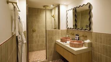 Un baño con ducha, dos lavamanos, un espejo y un perchero para toallas.