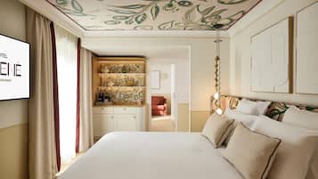 A hotel room with a bed, a TV, a desk with a patterned cabinet, and a red chair.