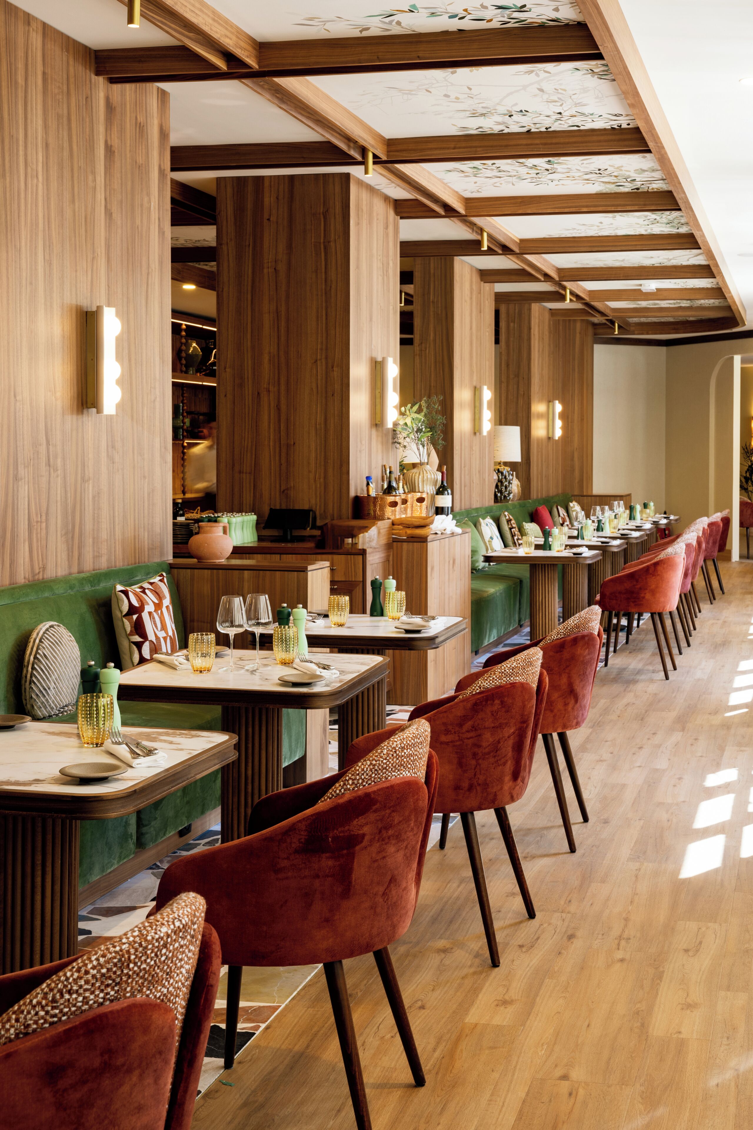 A restaurant with wooden paneling, green cushioned seating, and a long counter with red chairs.