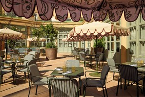 An outdoor patio with tables and chairs, large umbrellas, and potted plants. - Grand Hôtel Roi René Aix - MGallery Collection (Aix-en-Provence)