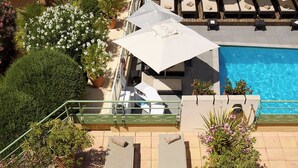 A rooftop pool area with lounge chairs, umbrellas, and a dining table with fruit. - Grand Hôtel Roi René Aix - MGallery Collection (Aix-en-Provence)