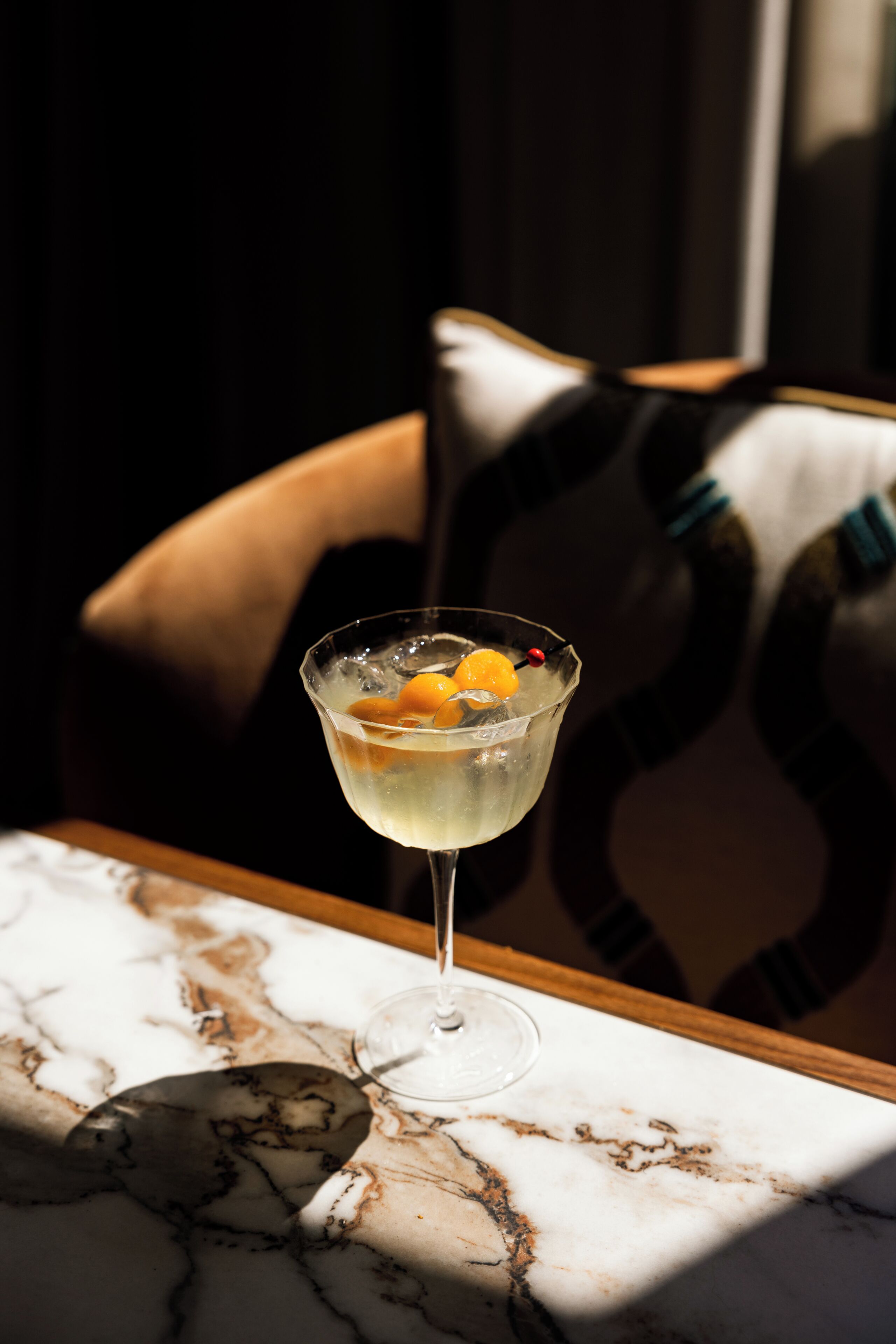A martini glass with a lemon twist on a marble table.