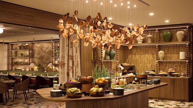 A restaurant with a buffet counter, wooden furniture, and various food items. - Grand Hôtel Roi René Aix - MGallery Collection (Aix-en-Provence)