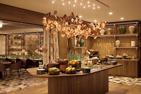 Un restaurant proposant un buffet, doté de meubles en bois et offrant une variété de plats.. Grand Hôtel Roi René Aix - MGallery Collection