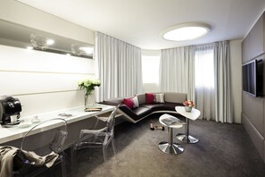 Junior suite, uitzicht op zwembad | Woonruimte | Een 32-inch lcd-televisie met satellietzenders en een televisie