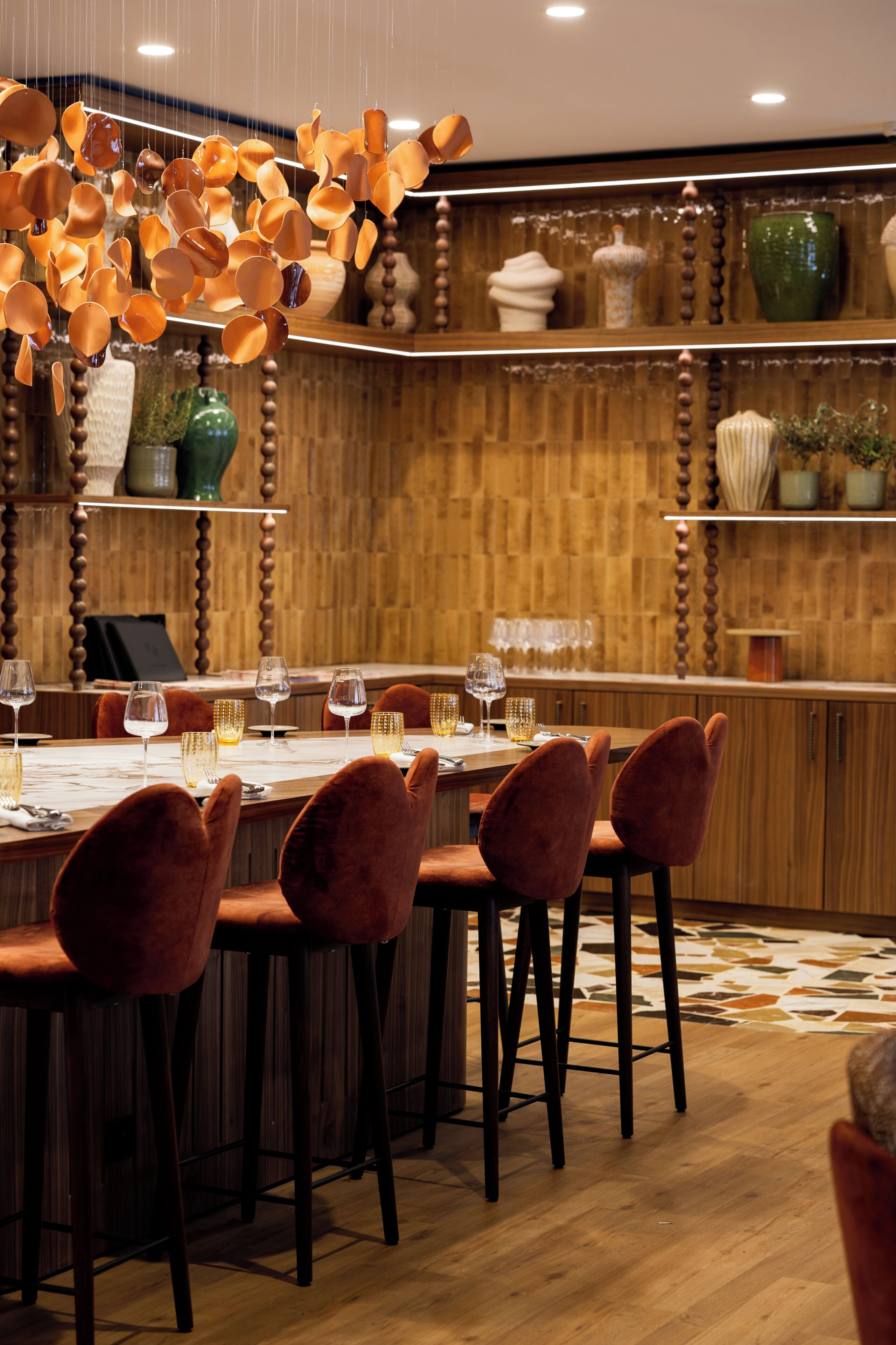 Un restaurante con interior de madera, una mesa larga con sillas y adornos colgantes.