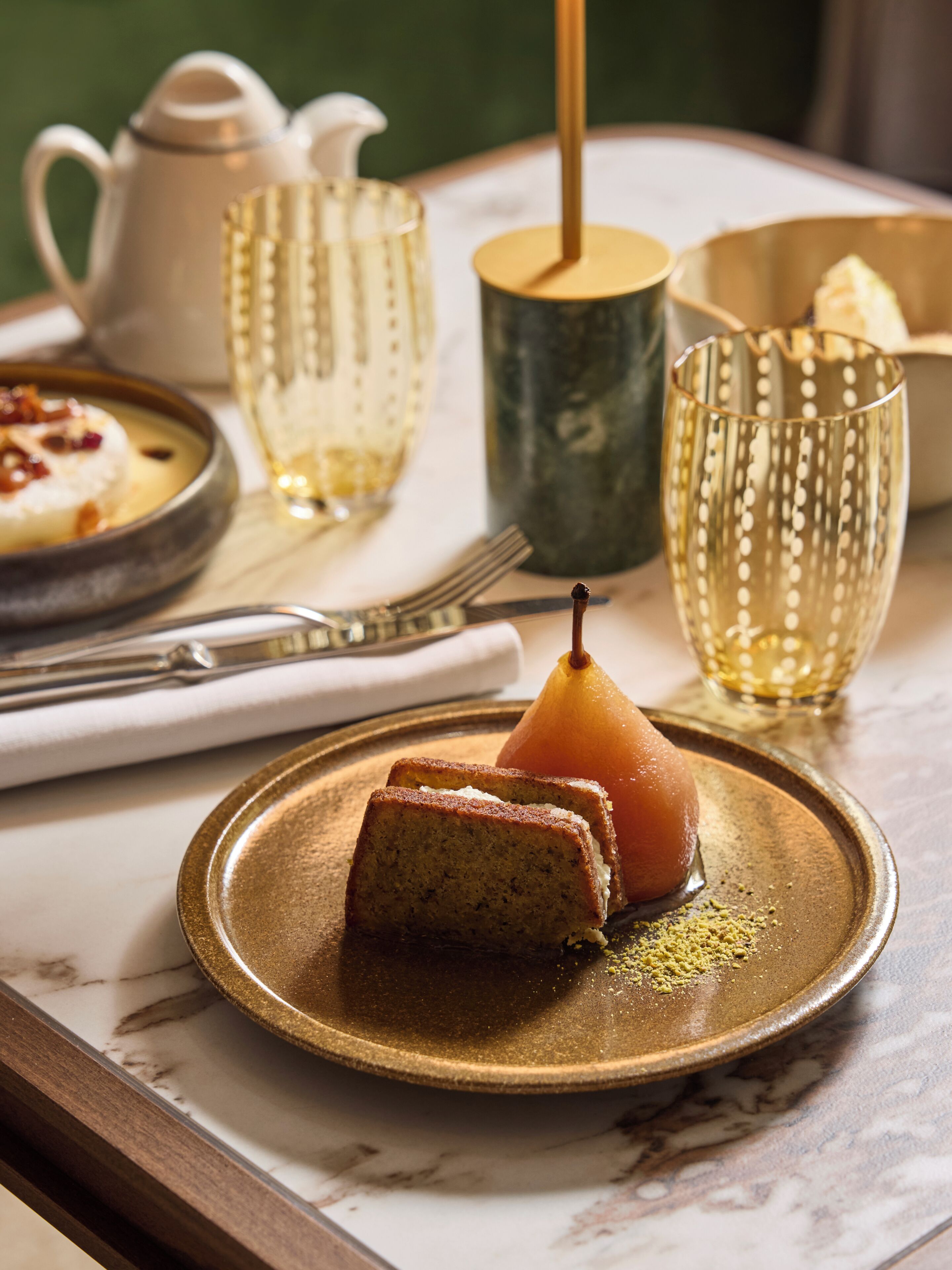 A table with a plate of food, a teapot, a cup, and a fork.
