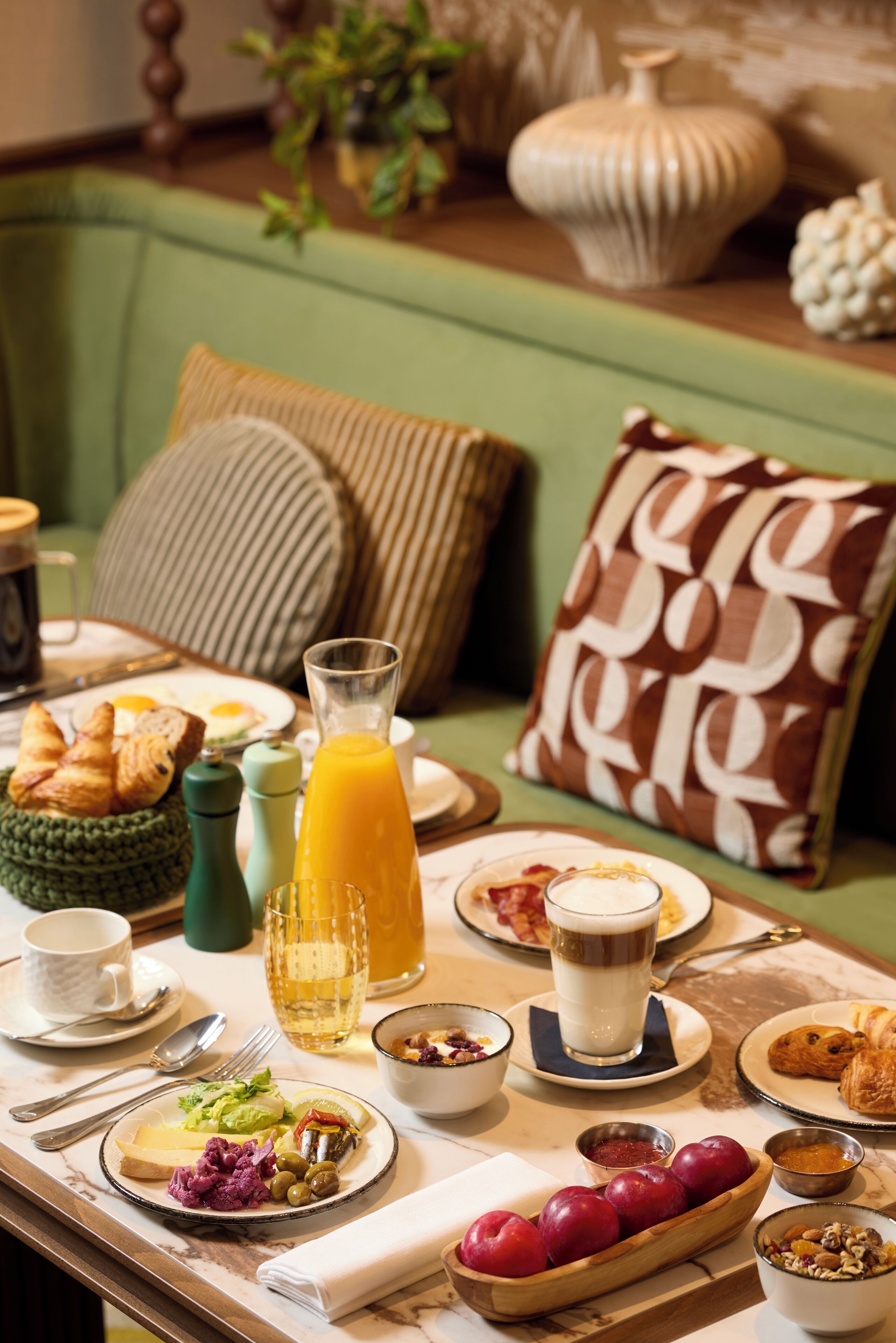 A breakfast setting with a variety of food items, a coffee cup, and a glass of orange juice on a table.