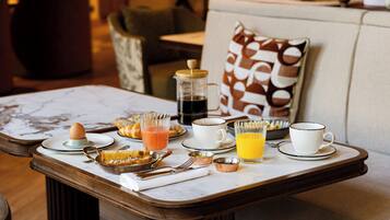 Une table de petit-déjeuner avec divers aliments, une cafetière et une tasse de café.