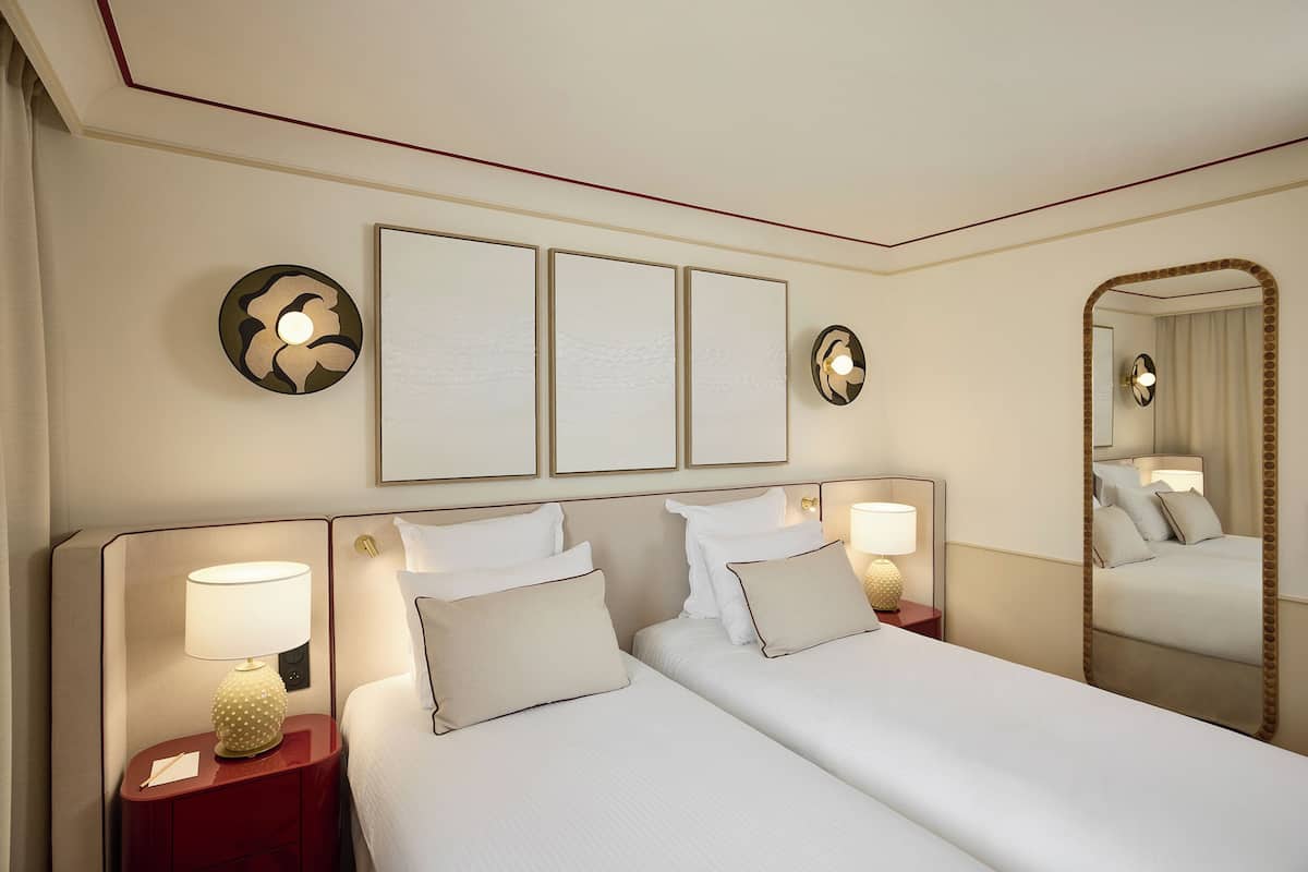 A hotel room with a large bed, two bedside tables, a mirror, and wall-mounted artwork.