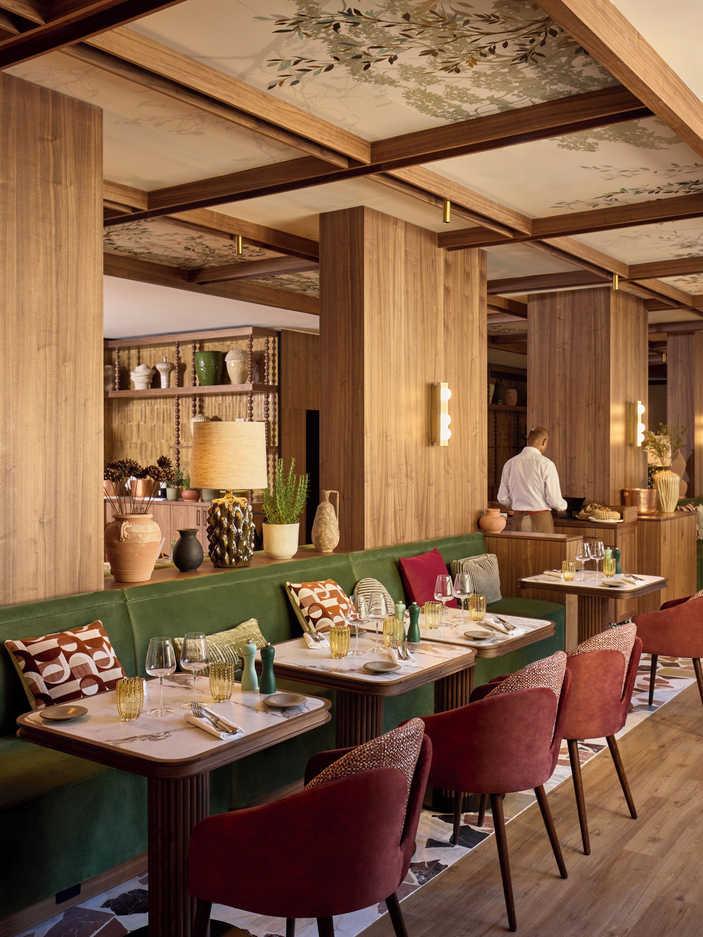 Un restaurante con vigas de madera, asientos verdes y una zona de bar.
