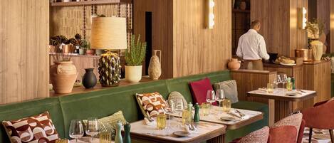 Un restaurante con vigas de madera, asientos verdes y una zona de bar.