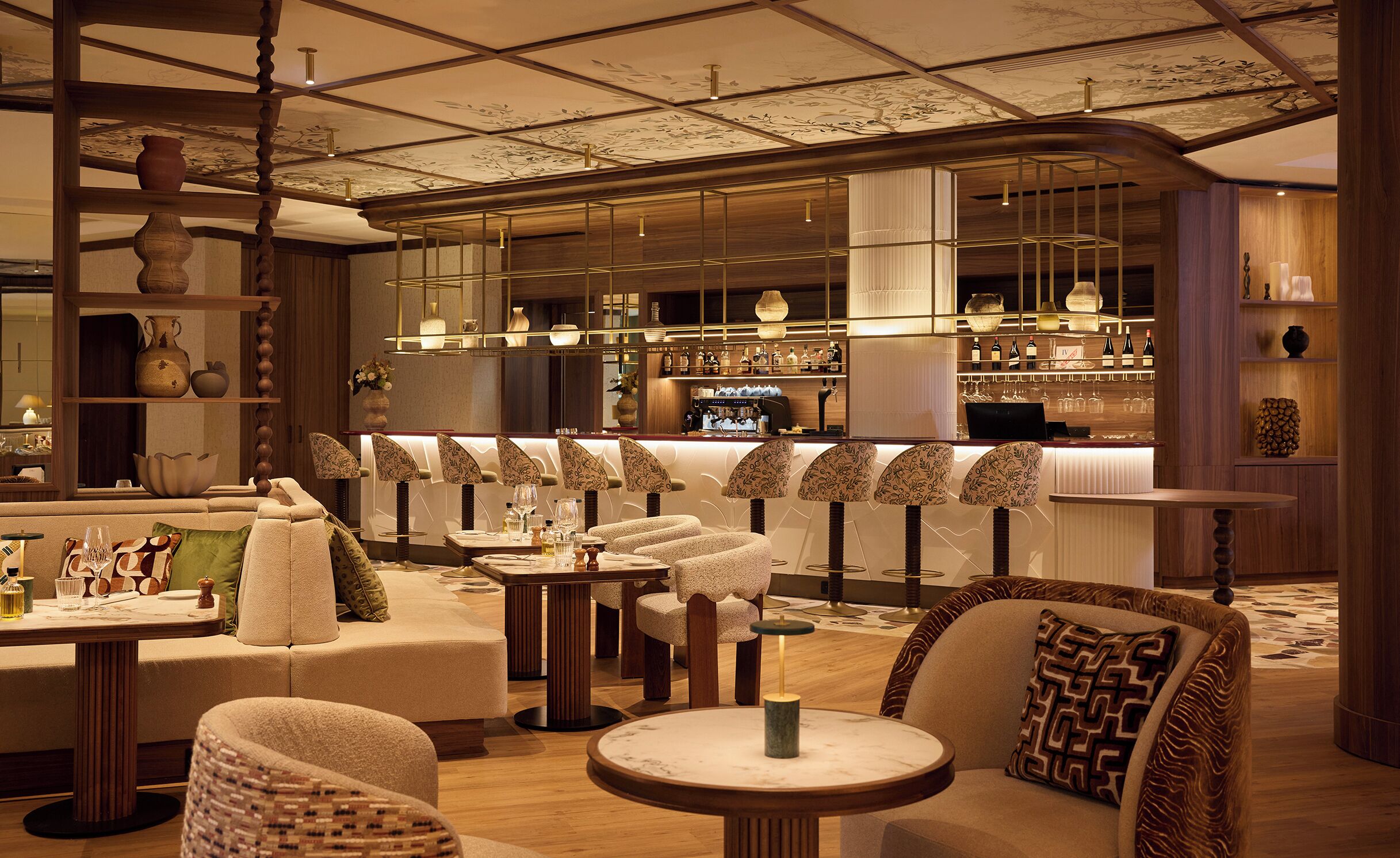 A modern bar area with seating, a bar counter, and a display of bottles.