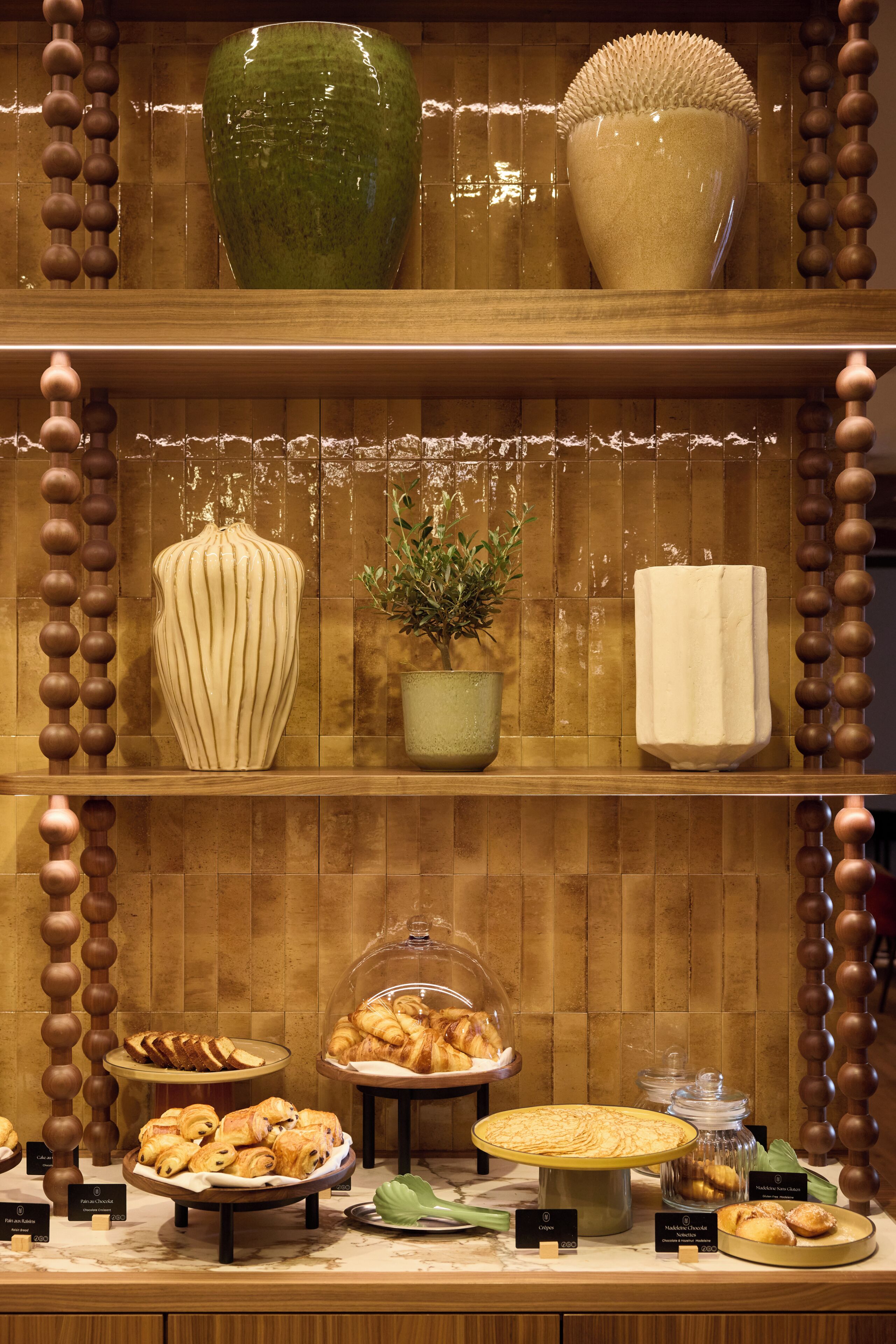 Un buffet proposant une variété de plats, notamment des pâtisseries, et agrémenté d’un grand vase vert.