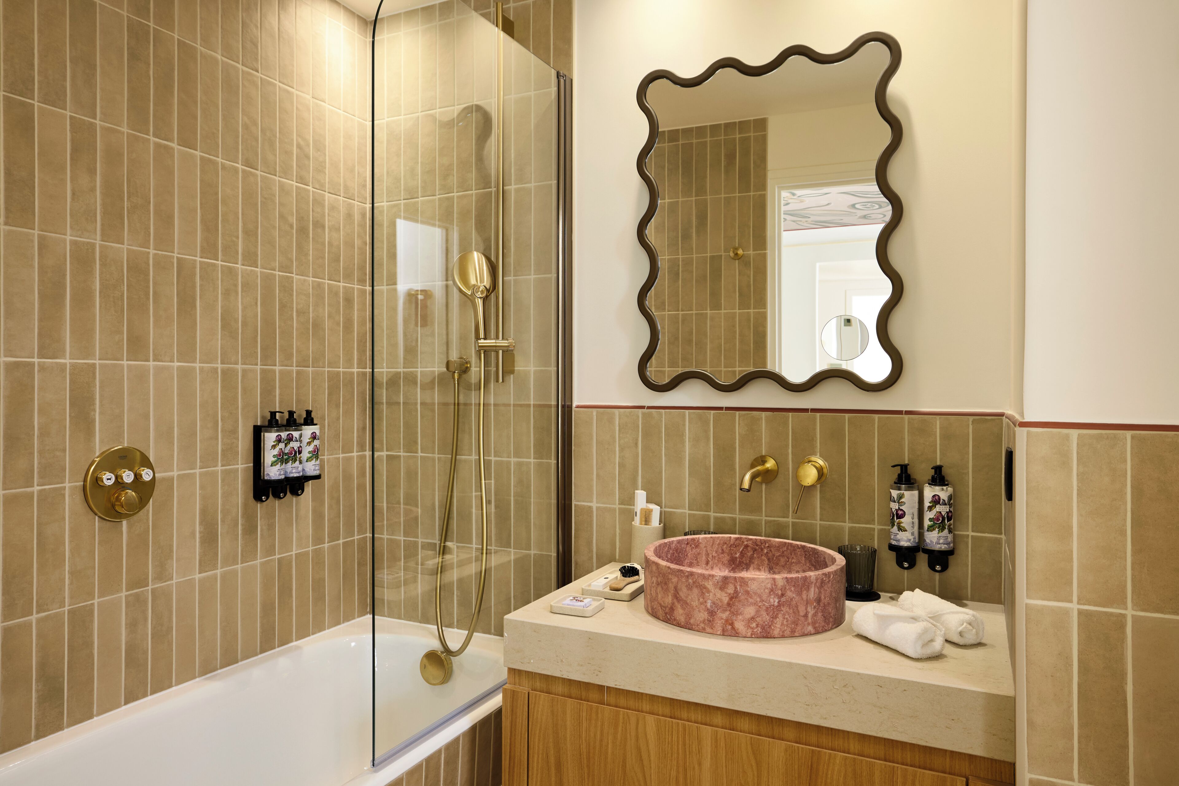 A bathroom with a bathtub, a shower, a vanity with a sink, and a mirror.