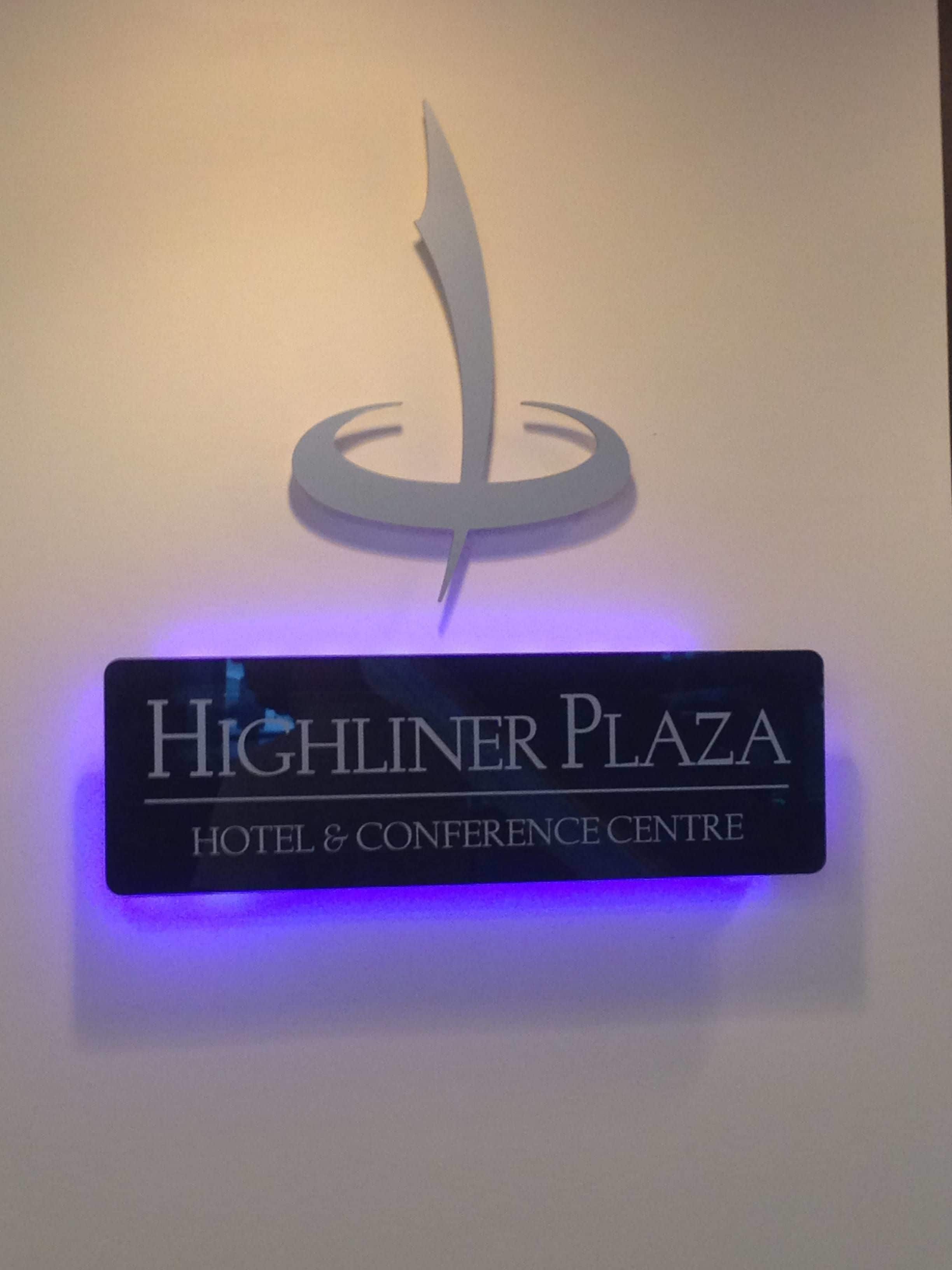 A sign for Highlander Plaza Hotel & Conference Centre with a stylized logo above the text.
