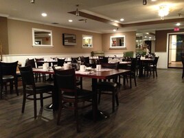 A dining area with multiple tables and chairs, equipped with table settings and light fixtures on the ceiling.