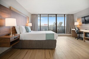 A hotel room with a large bed, a desk, a chair, and a TV.