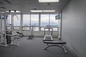 Un gimnasio con equipo de ejercicio, ventanas amplias y vistas al exterior.