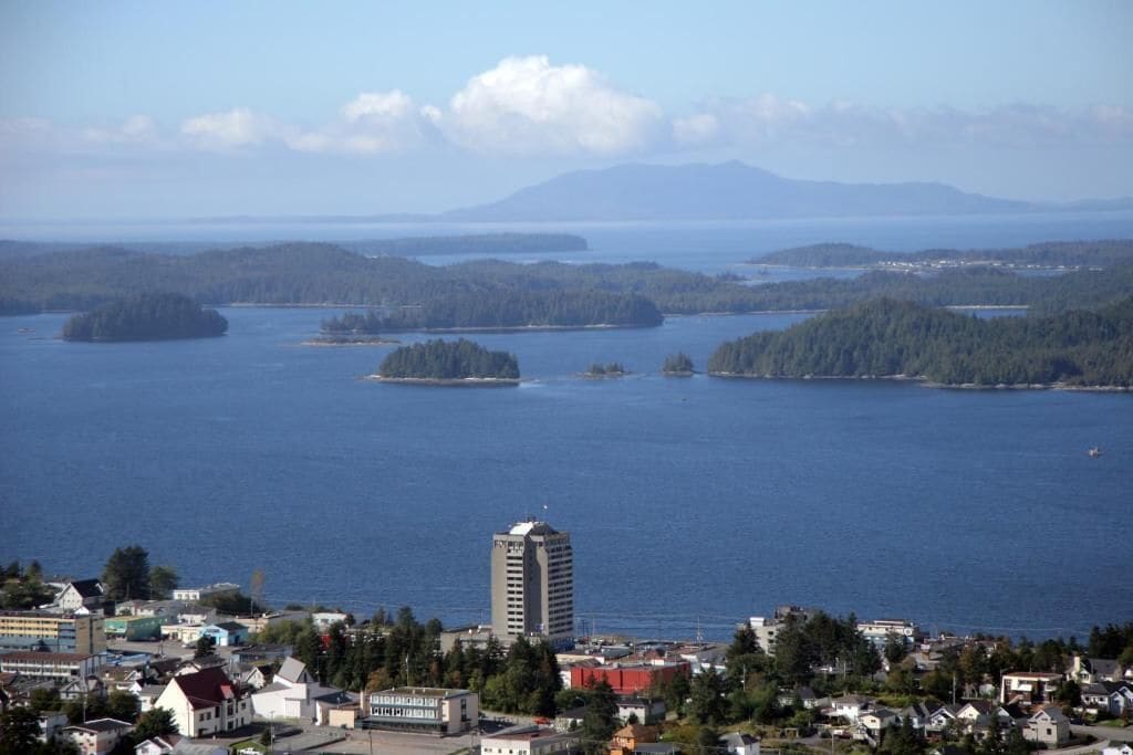 Un pueblo costero con un edificio destacado en primer plano y vistas al mar y a las islas en la distancia.