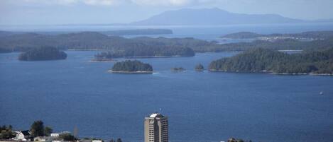 Un pueblo costero con un edificio destacado en primer plano y vistas al mar y a las islas en la distancia.