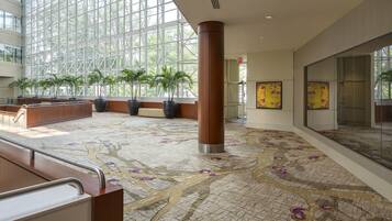 A spacious lobby with a high ceiling, large windows, and a patterned floor.
