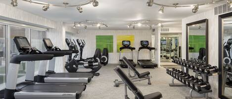 A gym with treadmills, elliptical machines, weight benches, and dumbbells.