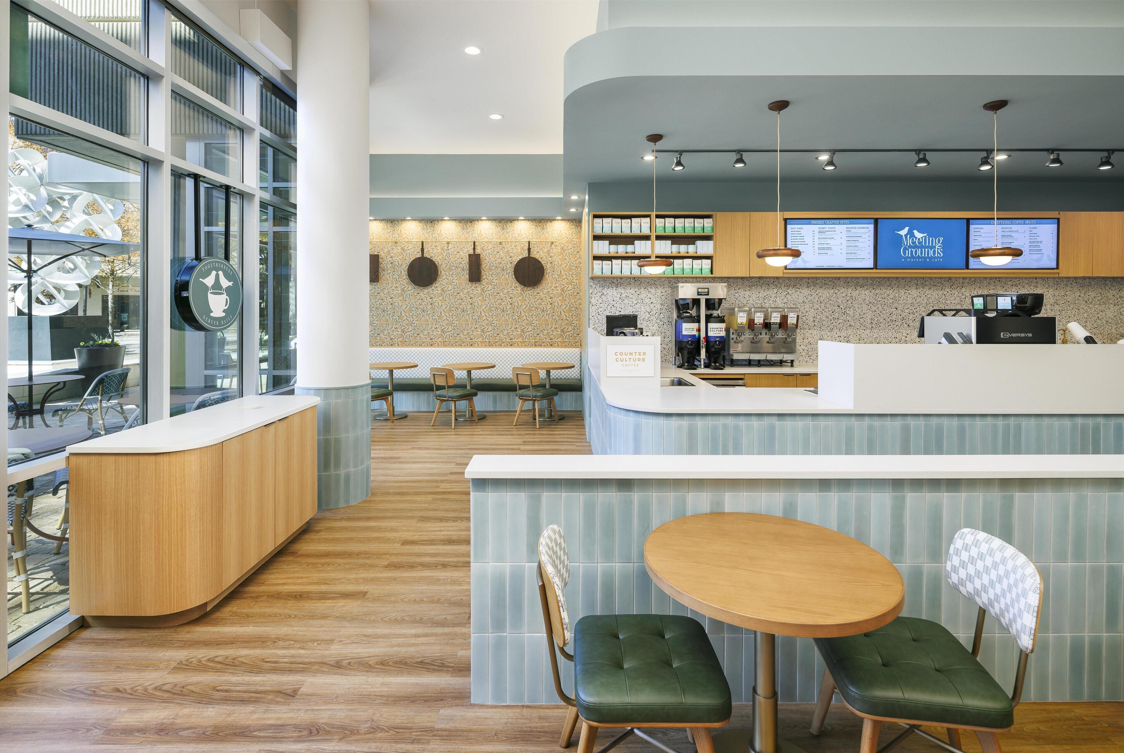 A modern cafe interior with a wooden counter, green cushioned seating, and a menu display.