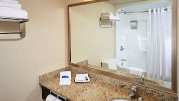 A bathroom with a granite countertop, a sink, a mirror, a towel rack, and a shower curtain.