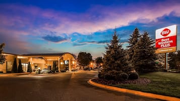 Welcome to the Guildwood Inn, where a covered driveway leads to the main building surrounded by lush greenery and mature trees.