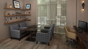 A modern office space with a desk, computer, and seating area. There are shelves with decorative items and a large window with a view. - Hampton Inn & Suites Asheville Biltmore Village (Asheville)