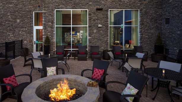 An outdoor patio with stone walls, a fire pit, and multiple seating areas with chairs and tables. - Hampton Inn & Suites Asheville Biltmore Village (Asheville)