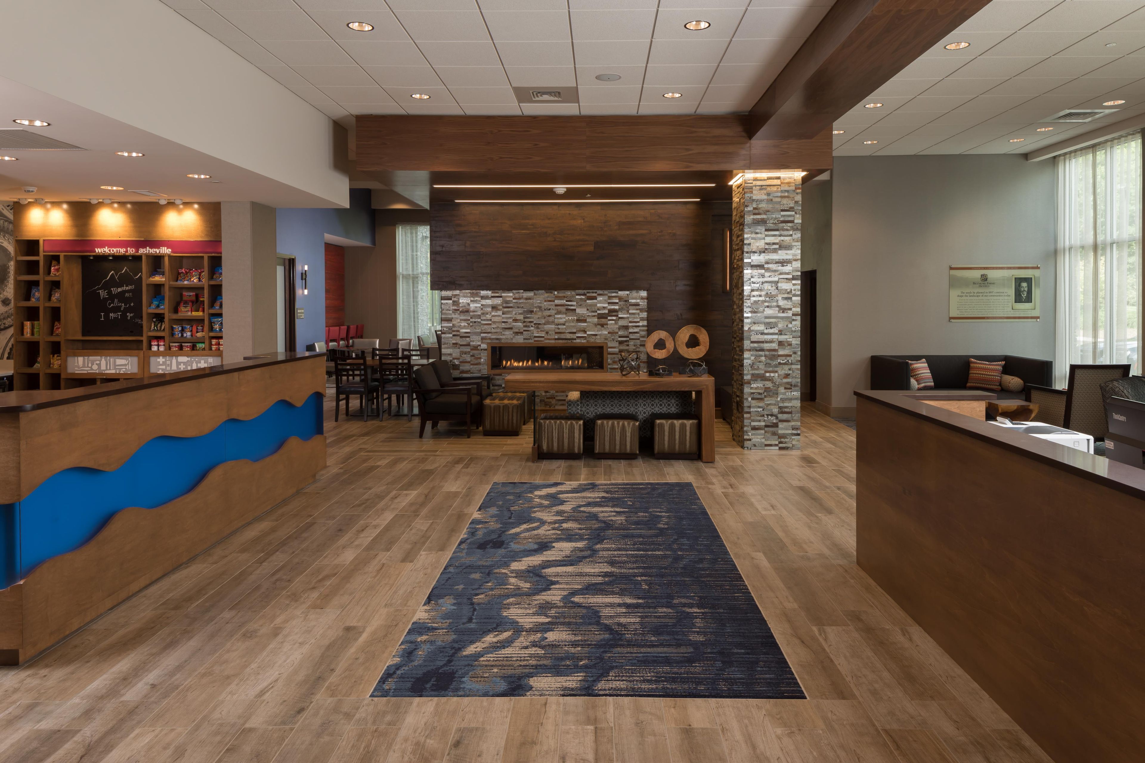 A hotel lobby with a reception desk, seating area, and a fireplace.