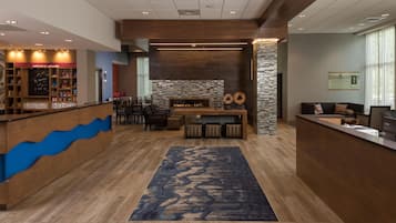 A hotel lobby with a reception desk, seating area, and a fireplace.